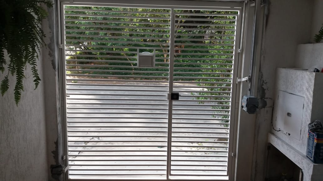Portão metálico vazado visto pelo interior da residência