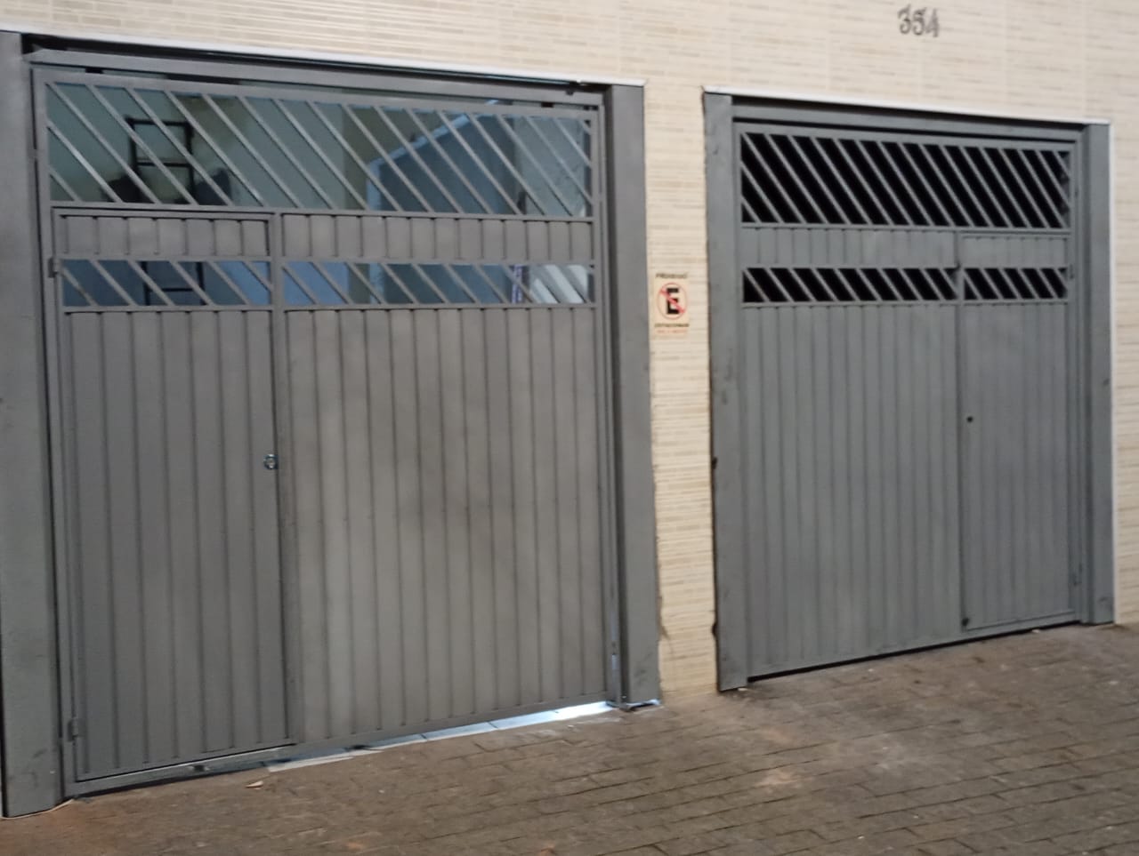 Conjunto de portões cinza instalado em fachada residencial